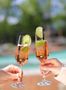 Zwei Menschen stoßen mit Rosésekt und Limette an