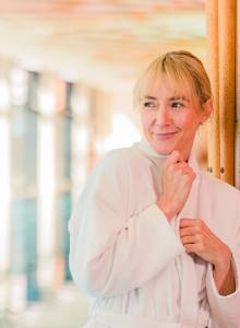 Frau im Bademantel steht im Wellnessbereich