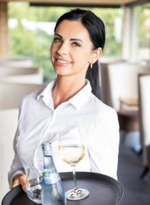Servicemitarbeiterin trägt ein Tablett mit Wasser und Wein