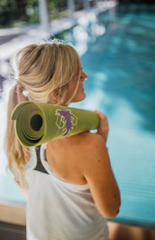 Frau hat eine Yogamatte über die Schulter gelegt