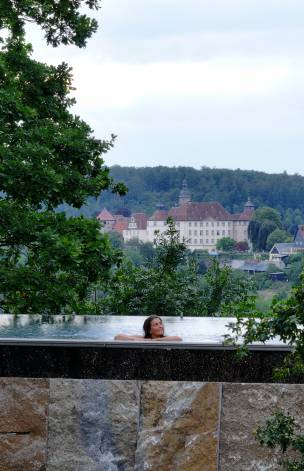 Frau im Infinity Pool mit Blick auf Schloss Langenburg