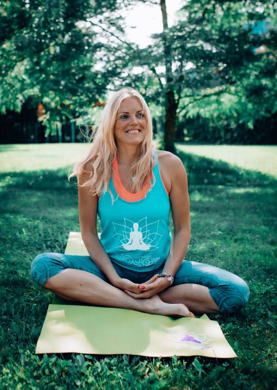 Yogalehrerin Petra Lösch sitzt auf einer Yogamatte im Garten