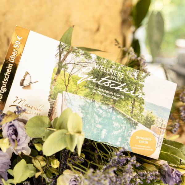 Geschenkgutschein liegt auf einem Blumenstrauß