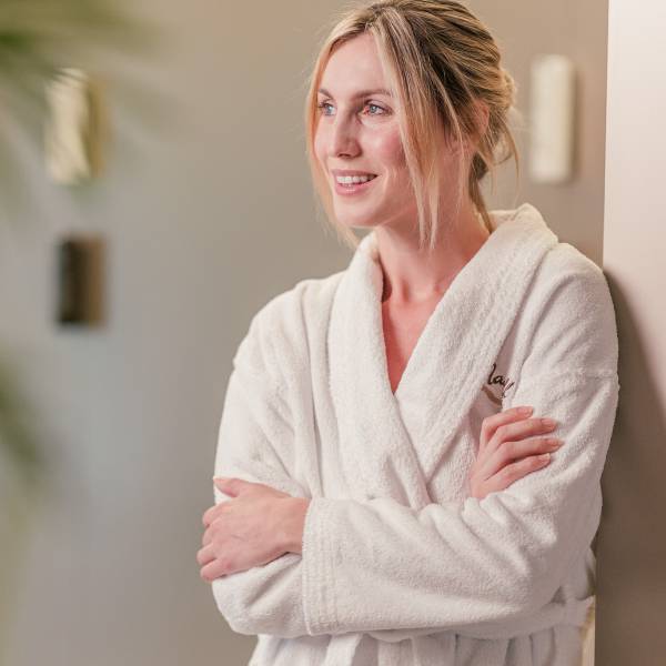 Frau im Bademantel steht im Wellnessbereich