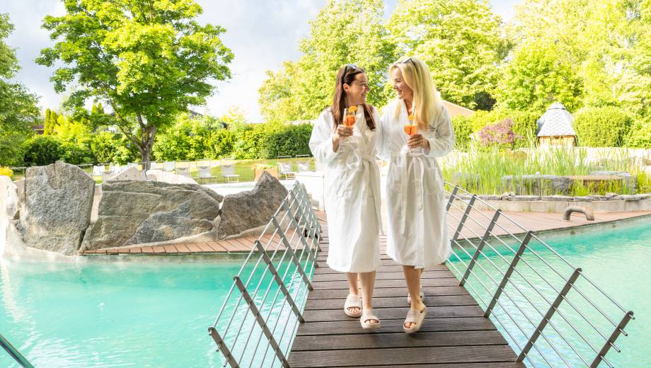 Frauen laufen mit Aperitif über das Naturbecken im Mawell Resort