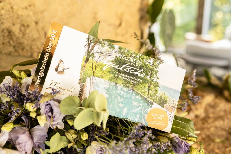 Geschenkgutschein liegt auf einem Blumenstrauß