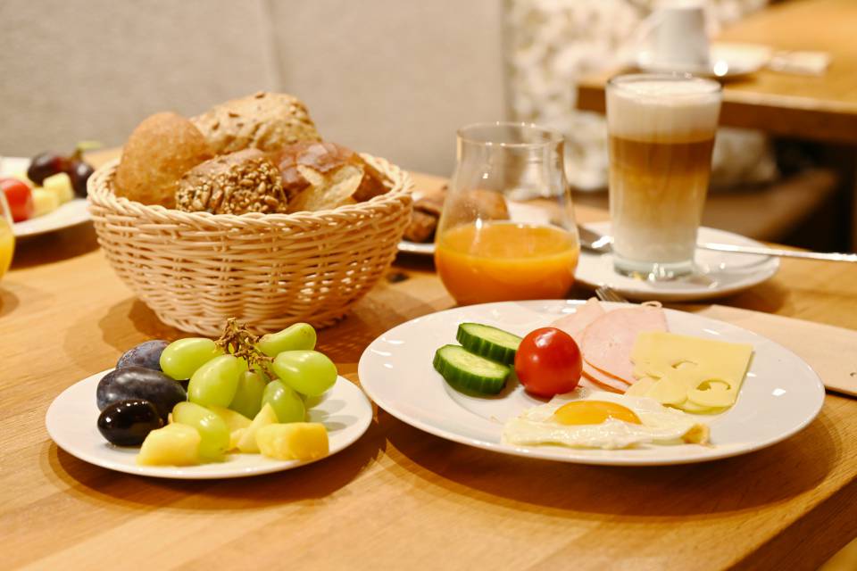 Frühstückstisch mit Obst, Kaffee und Brötchen